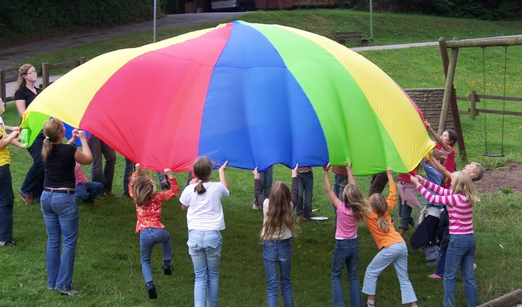 Children playing a group parachute game at a wedding – safe, supervised outdoor fun